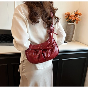 Vue détaillée du sac à main plissé rouge foncé avec nœud décoratif dans un décor de mode chic