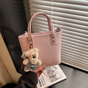 Detail of soft pink bucket bag with cute teddy bear charm and adjustable strap