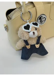 Detail of cute teddy bear charm with sunglasses on a beige handbag with high texture