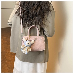 Detail of light pink pebble leather bucket bag with cute plush rabbit charm on a model
