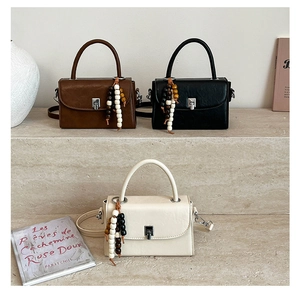 Three minimalist flap bags in brown, black, and beige with chic beaded tassels