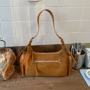 Detail of brown suede shoulder bag showing silver zippers and retro rivet hardware
