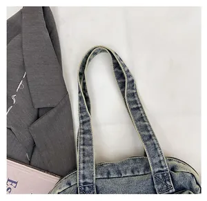 Detail of reinforced stitching on the blue denim tote bag handles with vintage wash