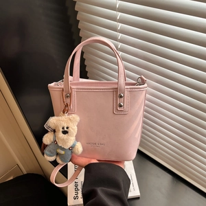 Detailed close-up of pink crossbody bag with metal buckle and plush bear charm
