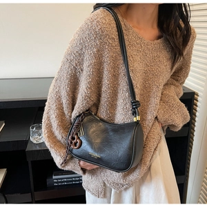Detail of black leather shoulder bag with decorative strap knot and golden branding