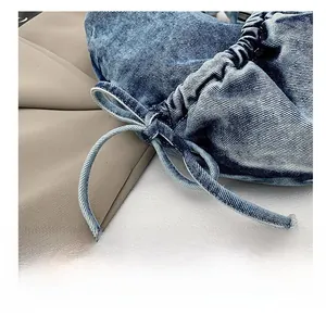 Detail shot of the drawstring design and pleated denim texture on this blue crossbody bag