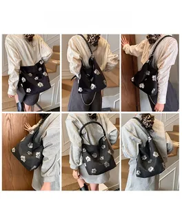 Detail showing a black bucket bag with silver sequin flowers and a metallic chain strap