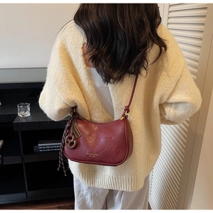Close-up of burgundy leather bag with silk scarf and gold ring charm detail