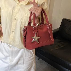 Gros plan sur le cuir grainé rouge et le pendentif étoile argenté du sac à main