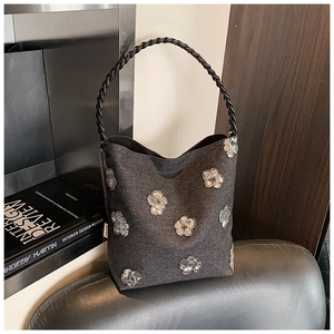 Detail of dark gray fabric bucket bag with sequin flower patterns and woven handle