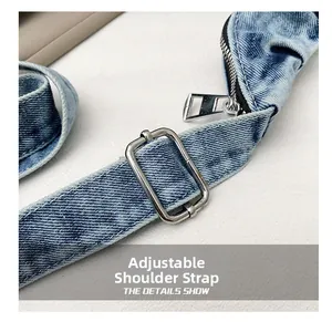 Detail view of adjustable denim shoulder strap with silver buckle and metal zipper