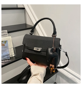 Close-up of black leather and herringbone fabric handbag with metal turn-lock detail