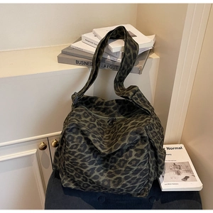 Detail view of large leopard print canvas tote bag on a blue corduroy chair