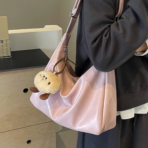 Roze kunstlederen draagtas met schouderband en pluche sleutelhanger op minimalistische achtergrond