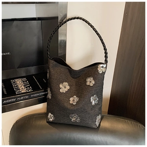 Detail of grey bucket bag with silver sequin flower embroidery and woven handle