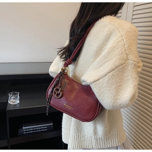 Close-up of burgundy retro leather underarm bag with knot strap and gold lettering detail