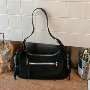 Detail of black suede dumpling bag with silver metal zippers and adjustable strap