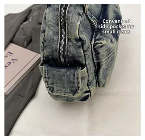 Detail of a vintage washed blue denim shoulder bag showing a functional side pocket with zipper