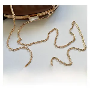 Close-up of golden metal frame handbag featuring a crystal clasp and fine chain strap