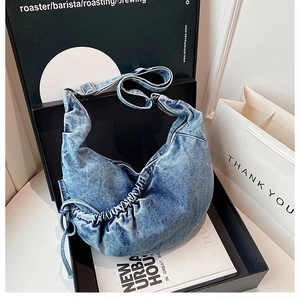Detailed close-up of blue wash denim crossbody bag featuring pleated cloud shape design