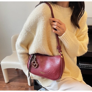 Deep red shoulder bag with textured leather, knotted strap and resin ring charm detail