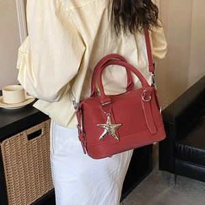 Sac polochon rétro rouge avec breloque étoile porté en bandoulière dans un cadre élégant