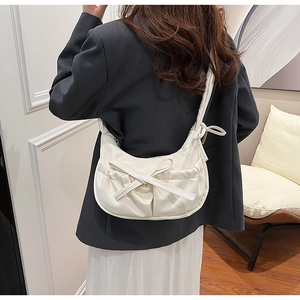 Vue détaillée du sac demi-lune plissé blanc crème avec nœud porté par un mannequin en intérieur