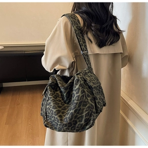 Detail view of large camo leopard print crossbody bag with adjustable wide strap on model