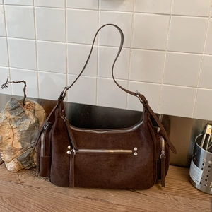 Detail view of dark brown suede handbag featuring silver zippers and metallic rivet accents