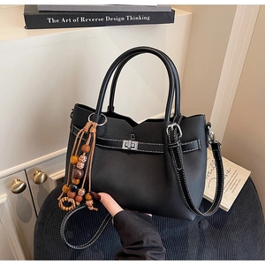Close-up of black tote bag with white contrast stitching and vintage bead charm