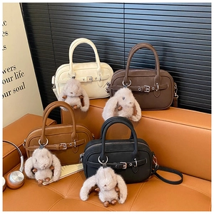 Close-up of vintage leather crossbody bags with cute rabbit charms on a sofa
