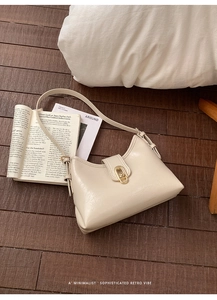 Close-up of cream underarm bag showing lychee leather texture and golden metal buckle