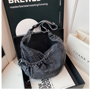 Detailed view of dark grey washed denim crescent crossbody bag with drawstring texture