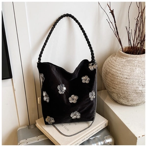 Detailed view of black velvet shoulder bag with silver sequin flowers and woven handle