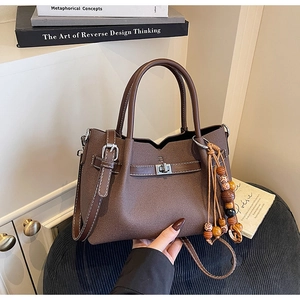 Detail of dark brown leather tote with silver twist lock and beaded tassel charm