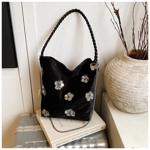 Detail of black velvet tote bag featuring silver sequin floral embroidery and twisted handle