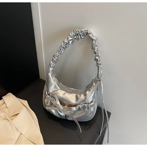 Détail du sac hobo argenté avec une poignée plissée et un ornement de nœud élégant