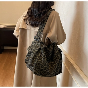 Detail showing the adjustable wide strap and buckle on the leopard print crossbody bag