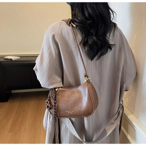 Brown semi-circle underarm bag with gold logo lettering and knot strap detail