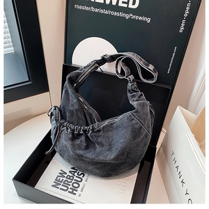 Detail of dark grey washed denim hobo bag with side drawstrings in a gift box
