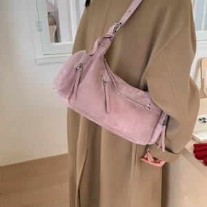 Detail of dusty rose suede crossbody dumpling bag with textured matte finish and wide strap