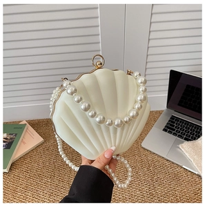 Detail of shell-shaped acrylic clutch bag with large pearl handle and shoulder chain strap