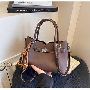 Detail of dark brown lychee textured tote bag with silver metal twist lock and bead charm