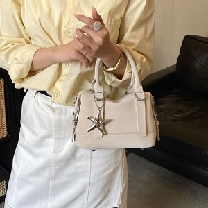 Détail du pendentif étoile de mer argenté sur un sac à main minimaliste blanc crème
