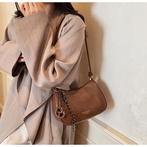 Side view of brown leather croissant bag with pretzel charm and knot handle detail
