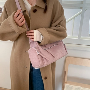 Detailed close-up of pink suede barrel bag with functional zippers and long pullers