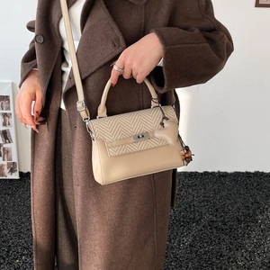 Close-up of minimalist crossbody bag with heart pendant and wooden beads on brown coat
