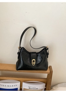 Detail of vintage black grain leather bag with glossy finish and gold oval buckle