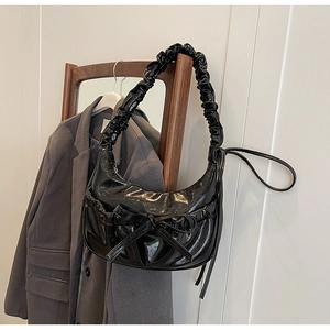 Détail du sac croissant noir avec décoration de nœud et bandoulière à plis froncés