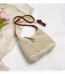 Détail de la texture crochetée et de la bandoulière en cuir brun du sac de plage crème